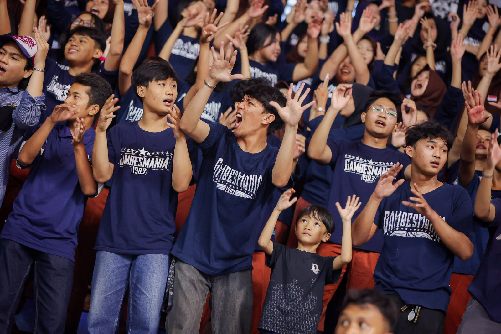 Anggota Gambesmania mengangkat tangan dan menyanyikan yel-yel saat mendukung tim basket putri SMAN 15 Surabaya di DBL Arena Surabaya.